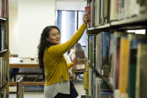 Library technician reaching for book